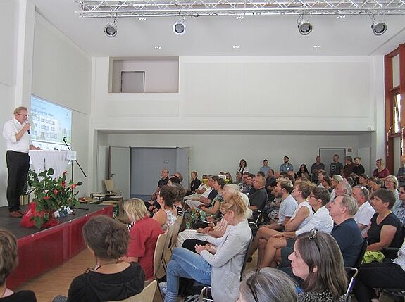 Bildtext: Bezirksstadtrat Ephraim Gothe spricht im neuen Veranstaltungssaal zu den Gästen. Bild: Dirk Maier, Planergemeinschaft für Stadt und Raum eG