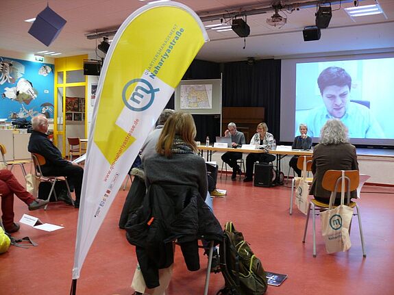 Johannes Raschke (Leinwand) von der Senatsverwaltung spricht über das Programm „Sozialer Zusammenhalt“. Mit dabei waren auch die Bezirksstadträtin Angelika Schöttler (vorne Mitte) und Corinna Lippert vom Bezirksamt (vorne rechts).(Bild: QM Nahariyastraße)