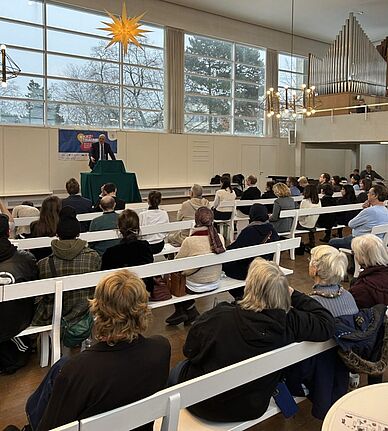 Stephan Machulik spricht vor Zuhörerinnen und Zuhörern im Saal der Brüdergemeinde beim Neujahrsempfang des Verbands für dezentrale Stadtteilarbeit Rixdorf.