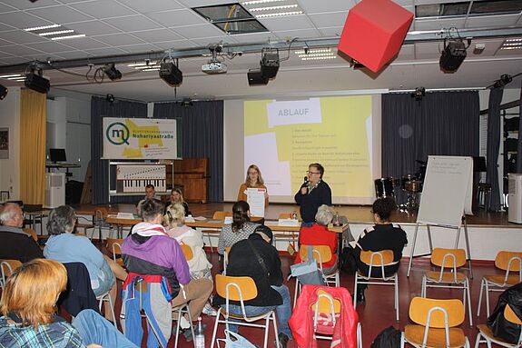 Menschen sitzen in einem Raum, während beim Nahariyaforum in der Nahariya-Schule eine Präsentation gehalten wird.