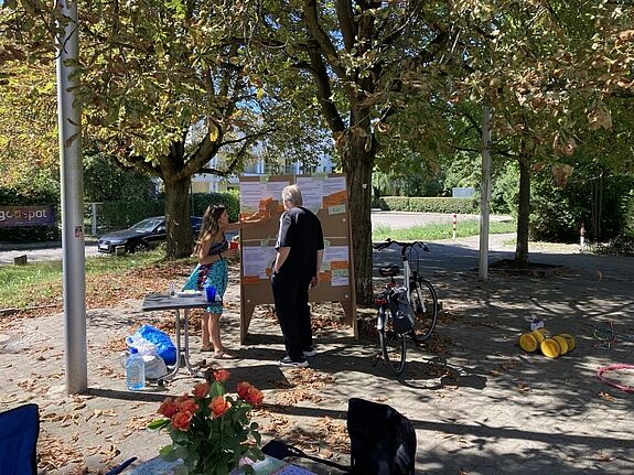 Zwei Personen stehen bei der Auftaktveranstaltung am 1. August 2024vor einer Pinnwand im Freien und besprechen Vorschläge zur Neugestaltung des Marktplatzes.