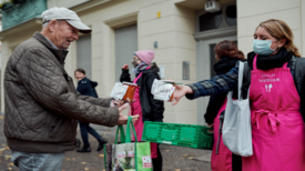 RESTLOS GLÜCKLICH-Mitarbeiterin gibt Essen an einen Mann aus.