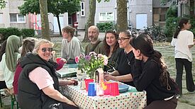 Anwohnende sitzen beim Opferfest an einem Tisch, der liebevoll gedeckt ist. 