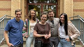 Fünf Projektbeteiligte des Bildungsprojekts „Außerschulische Lernorte“ stehen vor einem Gebäude der Herbert-Hoover-Schule im Berliner Quartier Reinickendorfer Straße /Pankstraße.