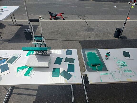 Auf einem Stand an der Straße liegen Materialen für einen Kunstdruck. 