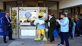 Staatssekretär Stephan Machulik, der ALBA-Albatros, Stadtrat Jochen Biedermann und ein Vertreter des ALBA-Teams stehen vor dem Eingang des Jugendclubs.