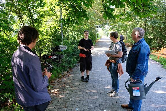 Mehrere Personen stehen bei einem Workshop im Grünen zusammen.