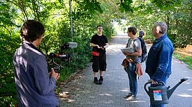 Mehrere Personen stehen bei einem Workshop im Grünen zusammen.