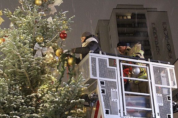 Dank des Leiterwagens der Feuerwehr kommen die Quartiersmanagerinnen bis an die Tannenspitze, um den Baumschmuck zu platzieren. (Bild: Birgit Leiß)
