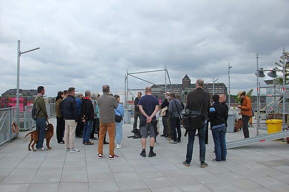 Eine Gruppe von Menschen nimmt an einer Führung auf der Dachterrasse des Zentrums für Kunst und Urbanistik (ZK/U) teil.