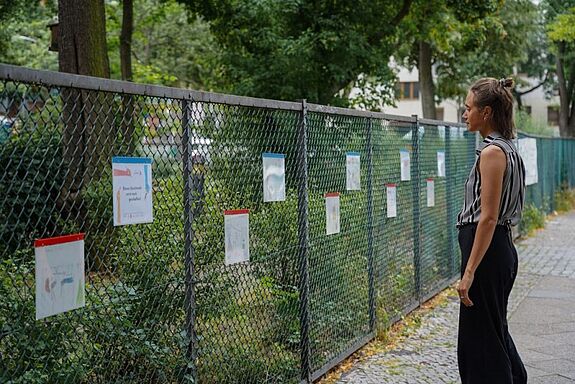 In der Kiezgalerien am Zaun hängen die Kunstwerke der Kinder aus der Löwenzahn-Grundschule aus. (Bild: AG.URBAN)