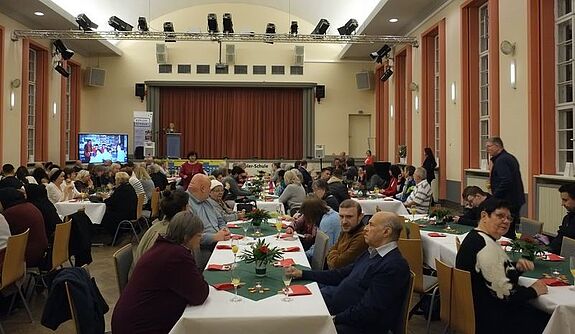 Die festlich gedeckten Tische in der Aula der Kepler-Schule sind mit Gästen der Dankesfeier gefüllt.