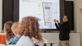 Eine Architektin präsentiert Schulkindern am Bildschirm einen Entwurf zur Neugestaltung des Schulhofs der Evangelischen Schule Neukölln.