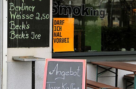 Ein Plakat im Schaufenster einer Bar auf der Brunnenstraße. Dominique Hensel / QM Brunnenviertel-Brunnenstraße