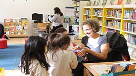 Leiterin Svenja Claussen spricht lächelnd mit einer Gruppe von Kindern in der Schulbibliothek der Eduard-Mörike-Schule.