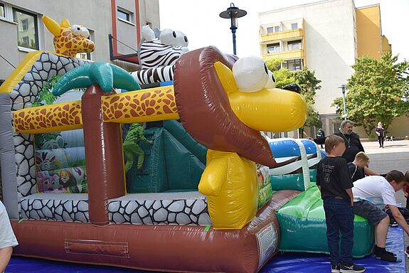 Beim Weltspieltag auf dem Boulevard Kastanienallee spielen Kinder vor einer bunten Hüpfburg mit Tiermotiven wie Löwe, Giraffe und Zebra.