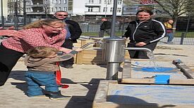 Jugendstadträtin Mirjam Blumenthal und der kleine Sohn von Baustadtrat Jochen Biedermann nehmen die Wasserpumpe in Betrieb. (Bild: Jens Sethmann)