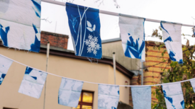 Fertig aufgehangene Fahnen hängen vor einem Haus. 