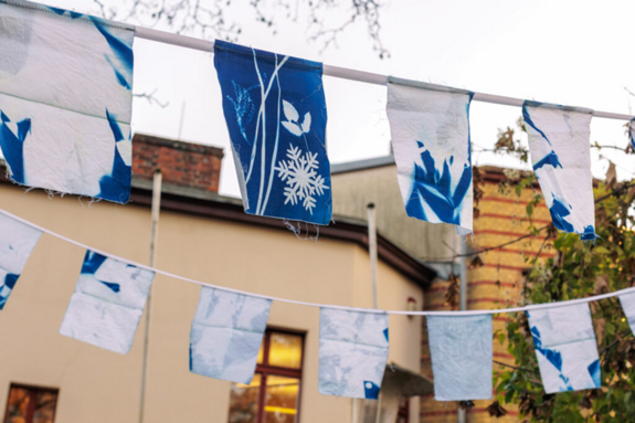 Fertig aufgehangene Fahnen hängen vor einem Haus. 