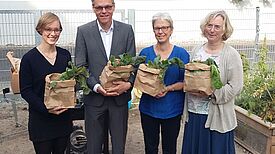 (Von links nach rechts) Eva Schuh (QM Schöneberger Norden), Jörn Oltmann (stellvertretender Bezirksbürgermeister und Bezirksstadtrat von Tempelhof-Schöneberg), Corinna Lippert (Bezirkliche Koordination Quartiersmanagement) und Christiane Heiß (Stadträtin des Bezirks) mit Gemüse aus dem Garten, Foto: gruppe F, QM Schöneberger Norden