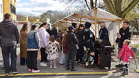 Viele Menschen stehen vor einem Grillstand an. 