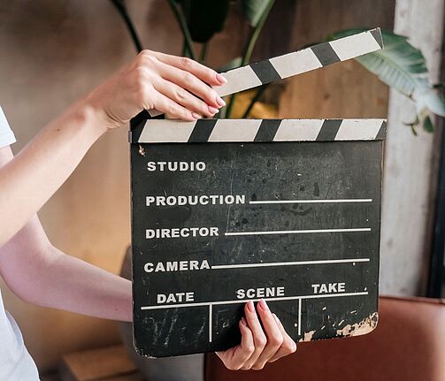 Eine Person hält eine Filmklappe vor sich.