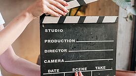 Eine Person hält eine Filmklappe vor sich.