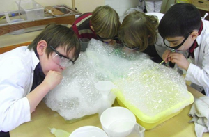Vier Kinder beugen sich über Seifenschaum.