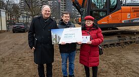 Staatssekretärin Ülker Radziwill und Bezirksbürgermeister Uwe Brockhausen (m.) überreichten auf der Baustelle des FACE CAMPUS einen Scheck über 350.000 Euro an den Superintendenten Volker Lübke (l.). (Bild: Kirchenkreis Reinickendorf / Hanna Halfon)