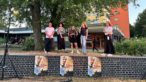 Fünf Personen stehen auf einer Mauer, die als Bühne genutzt wird und mit Plakaten des Films „Das Wunder von Bern“ beklebt ist.