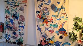 Zwei große Wandbilder aus Stoff zeigen eine bunte Unterwasserwelt mit Fischen. 