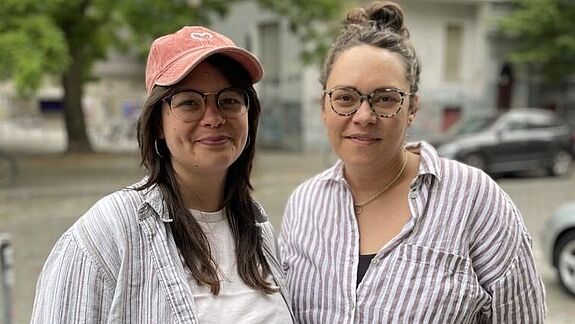 Zwei Frauen mit Brille, Anna Sukale und Runa Buchenberger, lächeln in die Kamera.