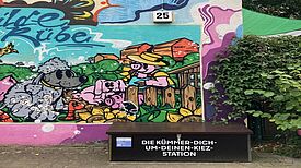 Eine Clean-Up-Box steht vor einer bunten Wandmalerei.