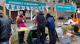 Menschen an einem Stand vom Projekt „Prima Klima“ auf Sperrmüll- und Tauschfest im Gespräch mit dem Projektteam. 