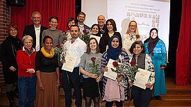 Vordere Reihe (v.l.n.r.): Nana Salzmann (Schulleiterin der Spreewald-Grundschule), Corinna Lippert (Bezirksamt), Heinz Georg Bruland (Dozent), Sarah Kamya (Dozentin), Nina Lutz (Projektleitung). Hinten: Oliver Schworck (Bezirksstadtrat) und zertifizierte Bildungsbotschafterinnen und -botschafter. Foto: Nina Lutz