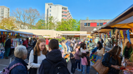 Besucherinnen und Besucher kommen zwischen Marktständen beim Frühlingsfest in Gropiusstadt Nord zusammen.