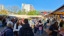 Besucherinnen und Besucher kommen zwischen Marktständen beim Frühlingsfest in Gropiusstadt Nord zusammen.