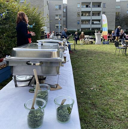 Buffet mit Speisen und Gästen bei der Einweihungsfeier des Rosengartens.
