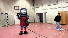 Maskottchen Ritter Keule und ein Trainer von Union Berlin in der Turnhalle der Hermann-Boddin-Schule.