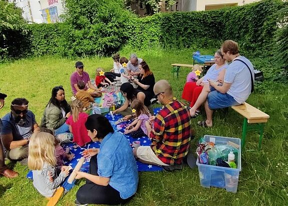 Kinder und Eltern gestalteten im Rahmen des Projekts „Familien in Bewegung: Unsere Bibliothek“ bunte Alebrijes auf der Wiese im Flughafenkiez. (Bild: QM Flughafenstraße)
