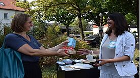 Dr. Katja Adelhof (links) überreicht Brot und Salz an Seira Kerber vom QM-Team Germaniastraße. (Bild: QM Germaniastraße)