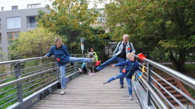 Eine Familie macht Bewegungsübungen auf einer Brücke.