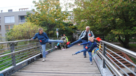 Eine Familie macht Bewegungsübungen auf einer Brücke.