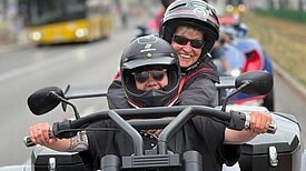 Zwei Personen fahren gemeinsam auf einem motorisierten Dreirad bei der Tour von Gitti und Gerda durch Berlin.