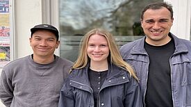 Drei Mitglieder des Projektteams „Aufbau von Selbstorganisation und Stärkung des Ehrenamts“ stehen vor einem Gebäude im Pank-Kiez lächelnd nebeneinander.