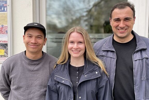 Drei Mitglieder des Projektteams „Aufbau von Selbstorganisation und Stärkung des Ehrenamts“ stehen vor einem Gebäude im Pank-Kiez lächelnd nebeneinander.