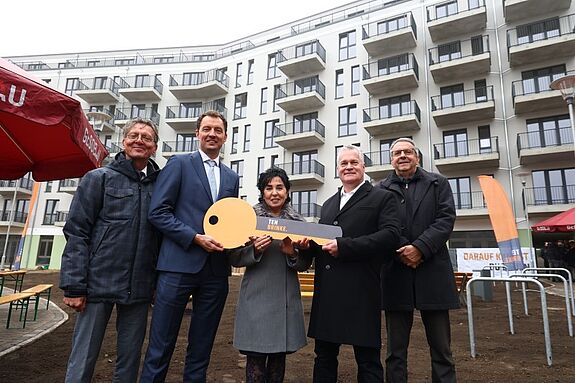 Vertreterinnen und Vertreter aus Politik, Kirche und Wohnungsbau posieren bei der Schlüsselübergabe für den FACE Campus mit einem symbolischen Schlüssel.