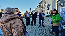 Anwohnende des Harzer Kiezes und Mitarbeitende der BSR stehen im Kreis am Treffpunkt der Aktion und reden miteinander.