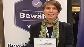 Ute Krüger von der Senatsverwaltung für Stadtentwicklung, Bauen und Wohnen hält die Urkunde für das Siegel "Bewährt vor Ort". 