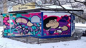 Auf den Außenwänden des Gemeinschaftspavillons „Zur Spinne“ sind große Bilder gemalt.
